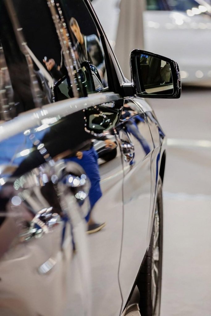 Close-up of a glossy black car door and side mirror after exterior detailing in the UAE