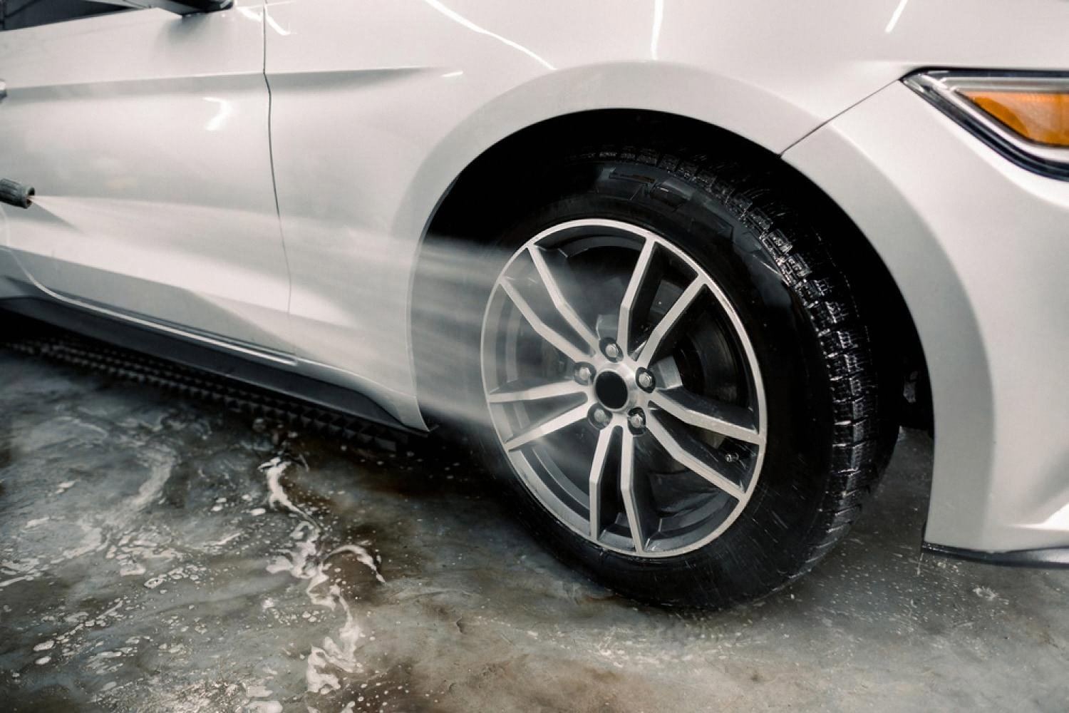 Alloy wheel and wheel arch being rinsed during an exterior detailing session